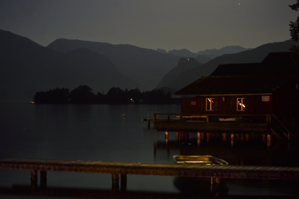 a dock with a boat in the water and mountains in the background