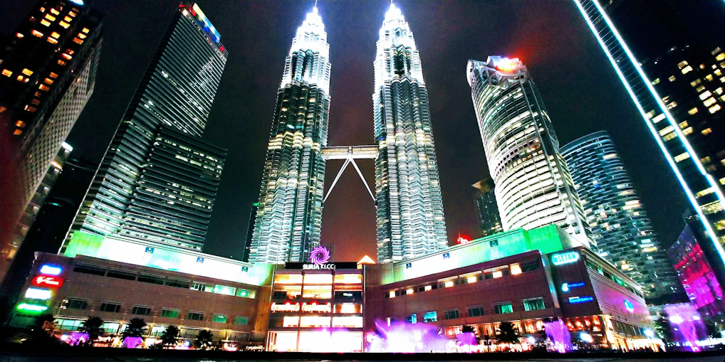 A panoramic view of Kuala Lumpur's skyline at sunset with the Petronas Towers glowing.
