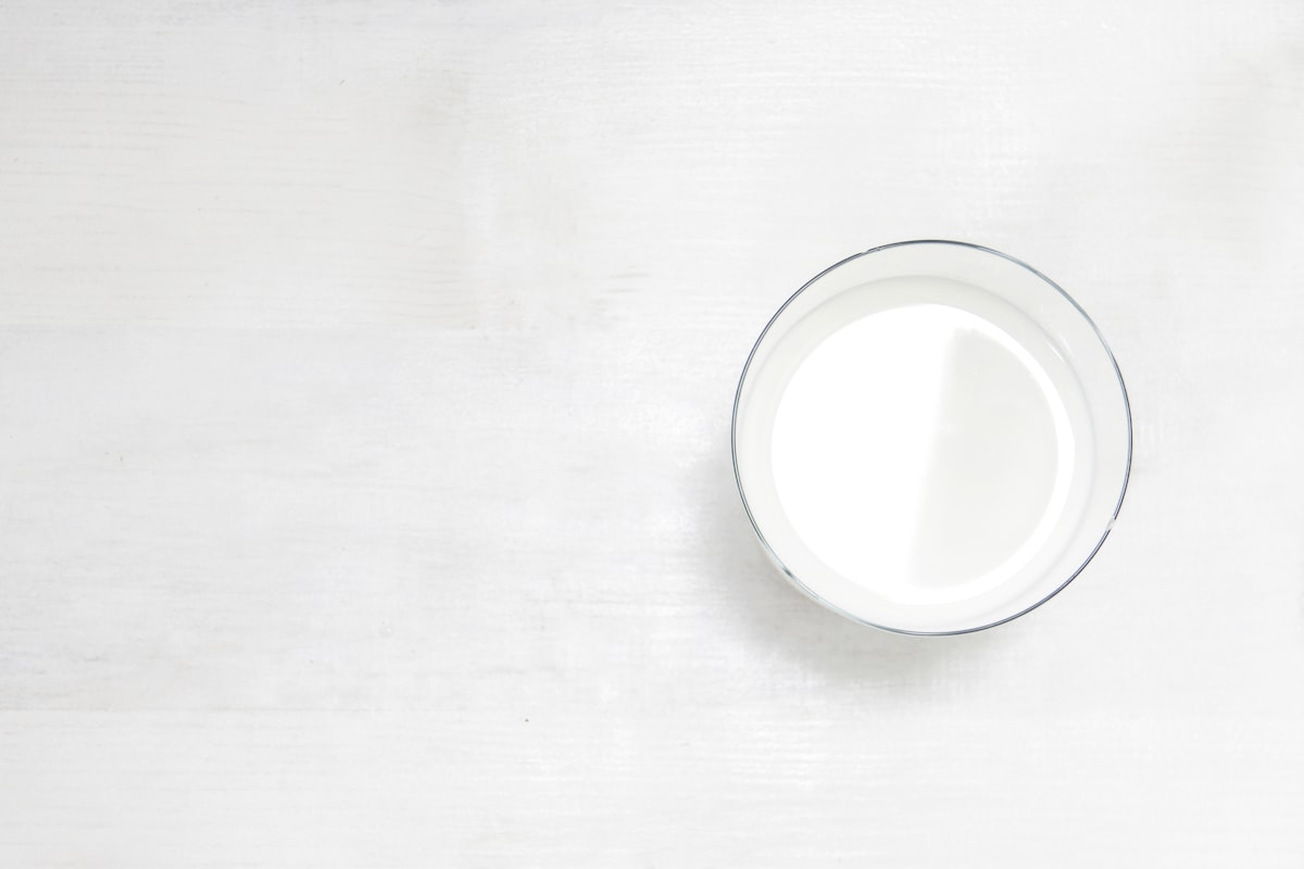 Glass of milk sitting on a table shot from above.