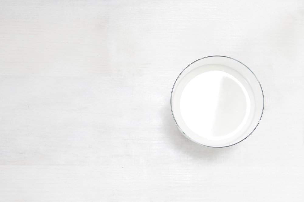 um copo de leite sentado em cima de uma mesa branca