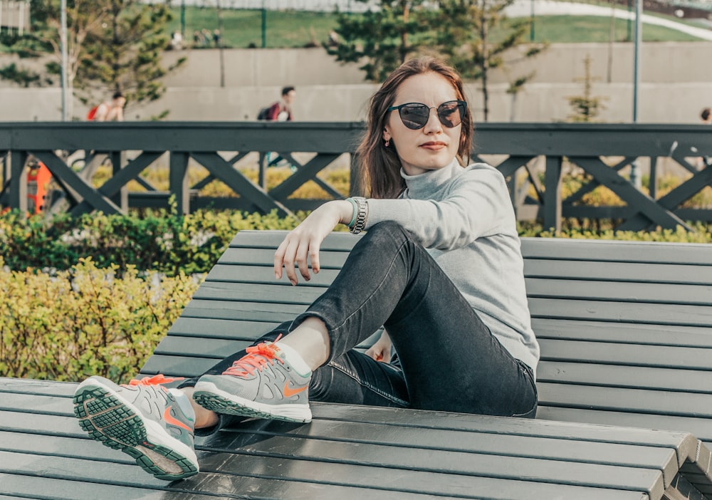 a woman sitting on top of a wooden bench