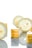 A minimalist composition featuring slices of lemon interspersed with small layered lemon cakes. The bright yellow and white hues create a fresh and vibrant atmosphere. The cakes have a glossy top layer, and the reflection on the surface adds an elegant touch.