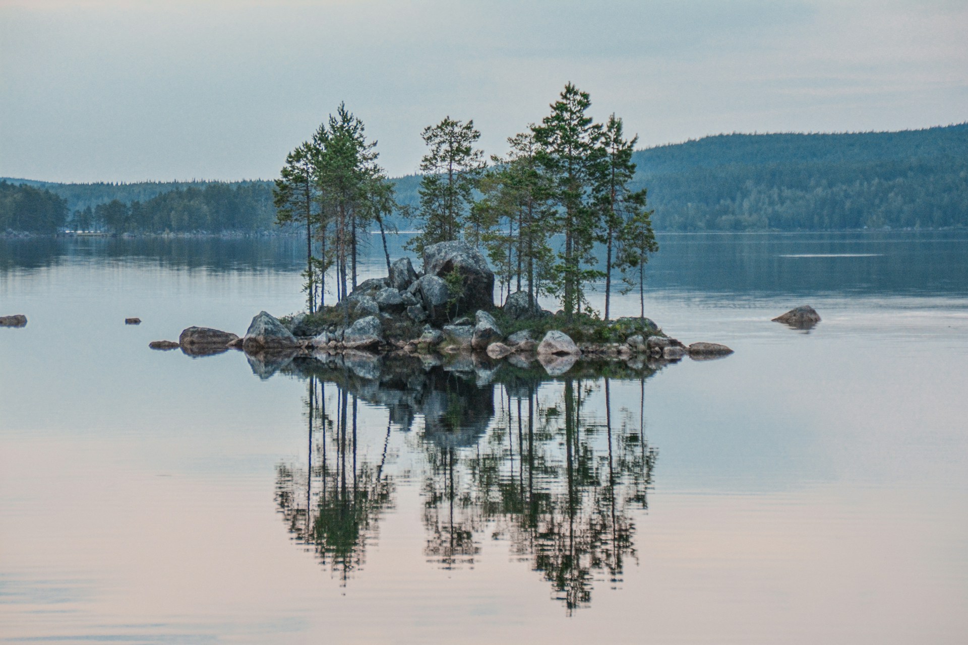 Serene Swedish lake landscape with crystal clear water reflecting a soft dawn sky