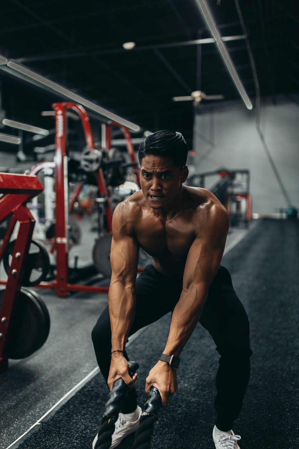 muscled man holding two black ropes