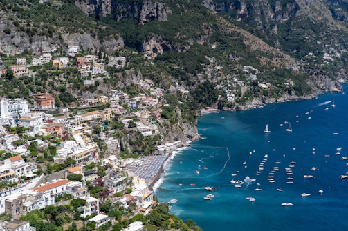 A cinematic aerial view of a vibrant coastal town with boats and turquoise waters.