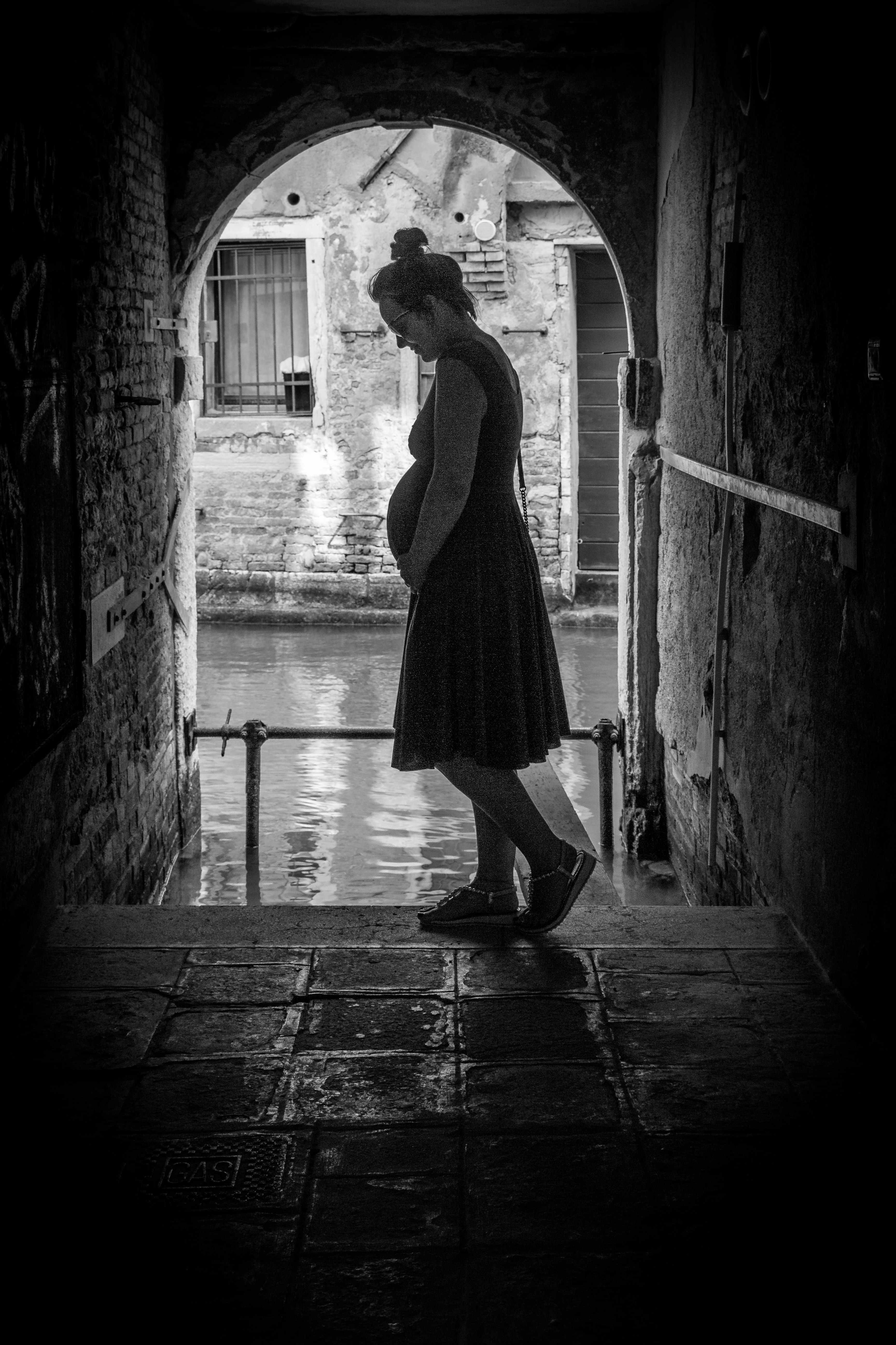grayscale photography of pregnant woman standing on tunnel