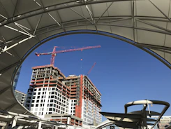 Engineers reviewing blueprints on a construction site with cranes and building frames.