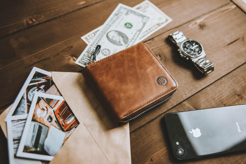 a wallet sitting on top of a wooden table next to a cell phone