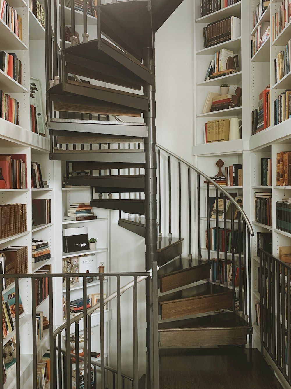 a spiral staircase in a library with bookshelves