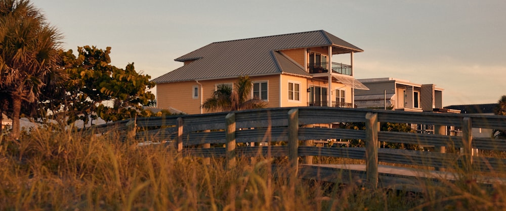 a house on a beach with a fence in front of it