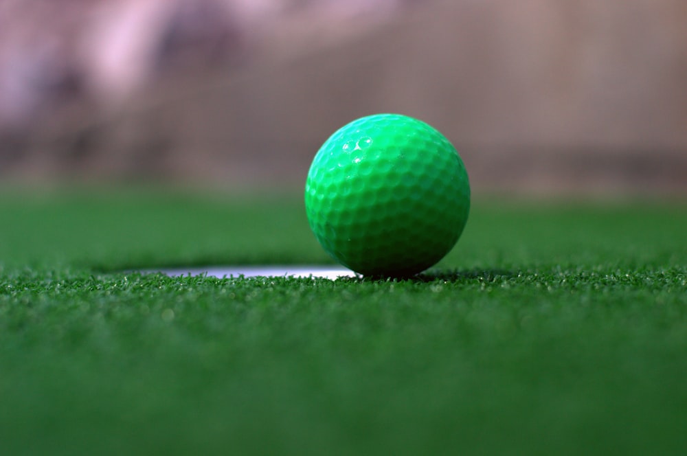 une balle de golf verte posée au sommet d’un champ vert