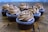 Six chocolate cupcakes topped with swirled chocolate frosting and chocolate chips are arranged on a wooden surface. The cupcakes are in brown liners with a textured appearance. The background is softly blurred, highlighting the focus on the cupcakes.