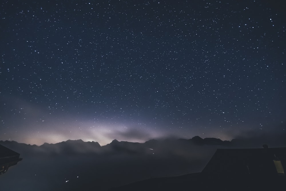 the night sky with stars above a mountain range