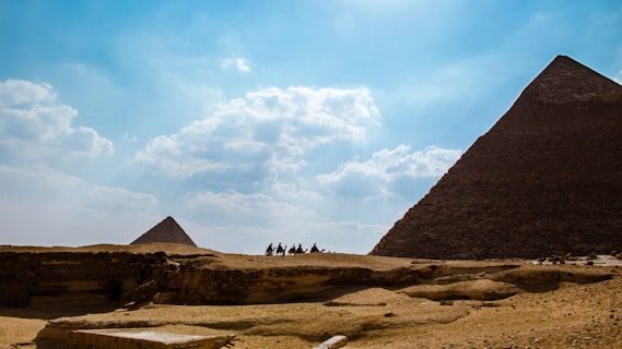 people riding camels near pyramids