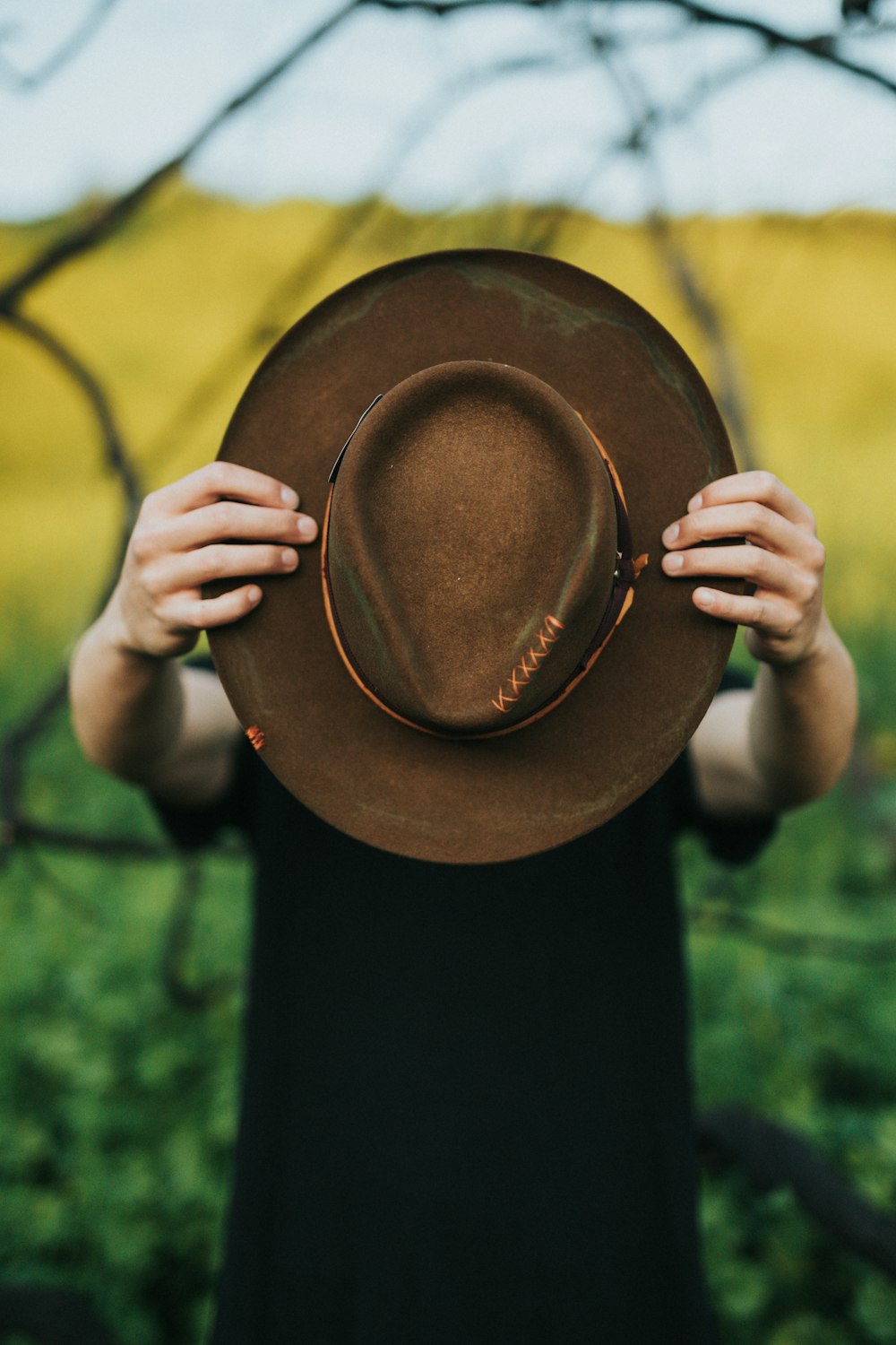 personne tenant un chapeau brun