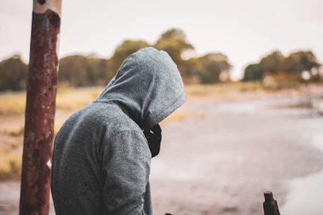 man in gray hoodie standing near post
