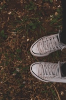 A pair of worn-in sneakers on a grassy park bench, ready for a walk.