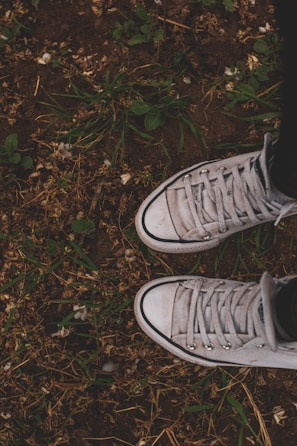 A pair of worn-in sneakers on a grassy park bench, ready for a walk.