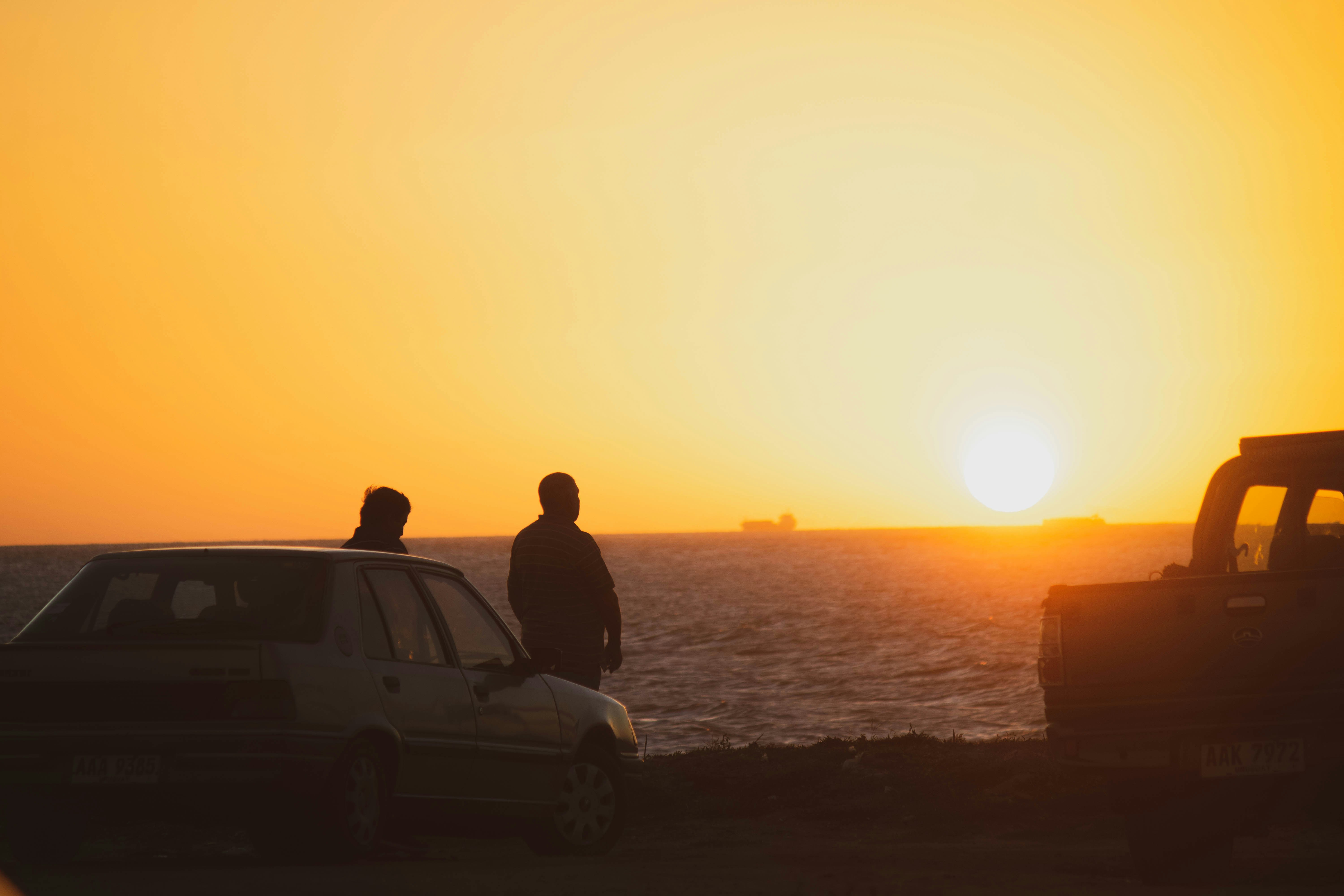 two persons beside car, Two man watching the sunset in Uruguay