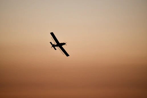 A small aircraft soaring gracefully above a golden sunrise runway, capturing the thrill of early morning flight.