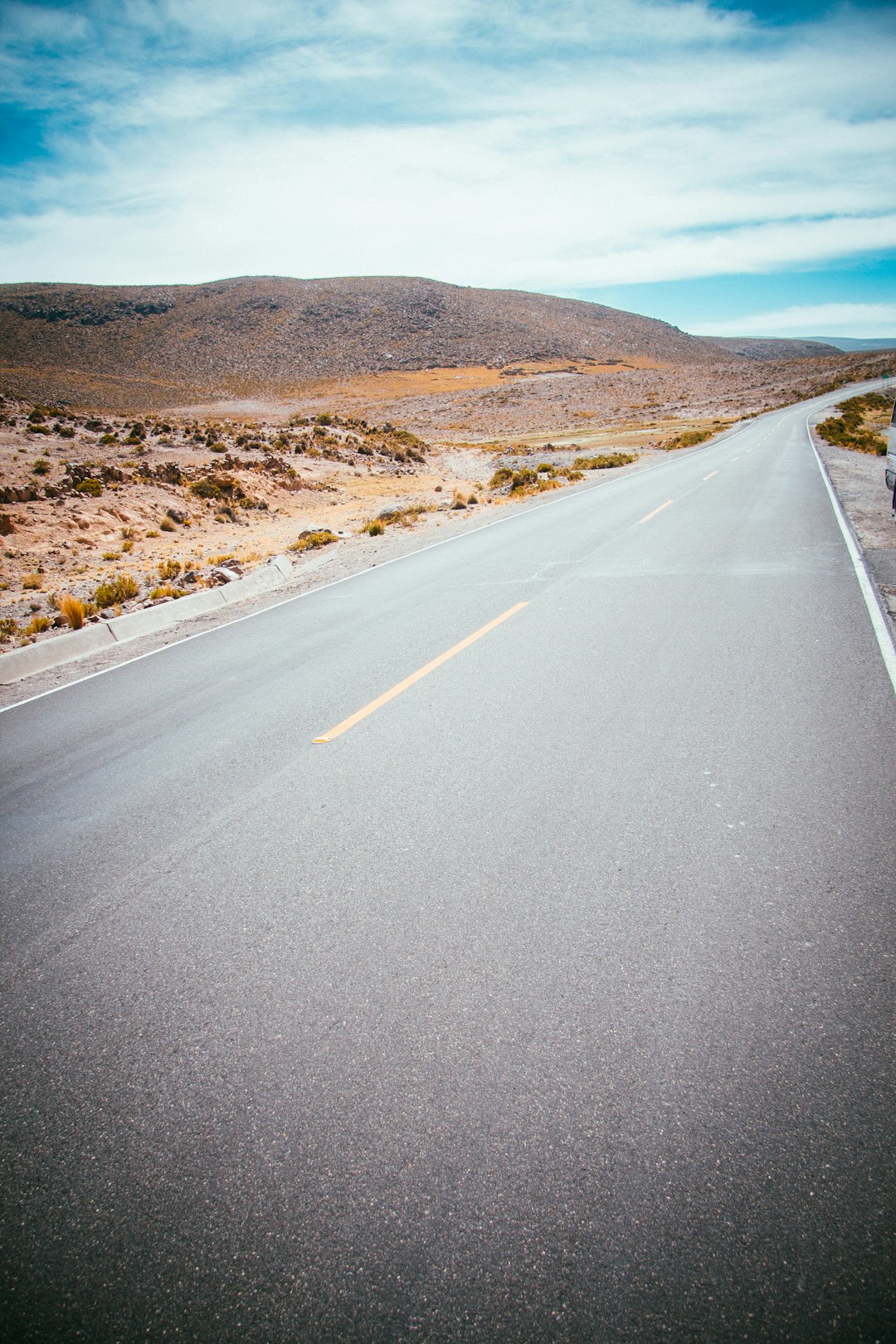 gray concrete road between mountain at daytime