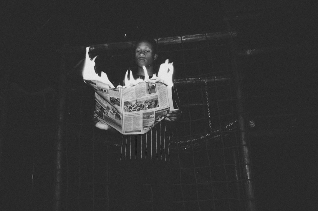 man holding burning newspaper