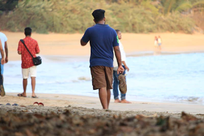 Group of friends laughing and walking barefoot near the water wearing Summer Shores aqua shoes.