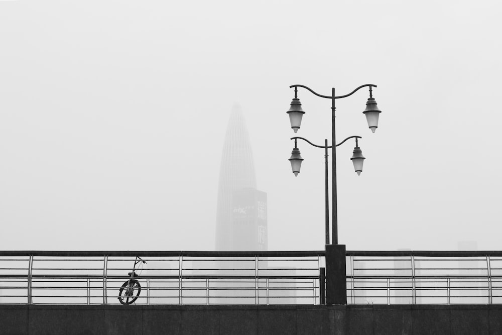 grayscale photo of bicycle on concrete bridge
