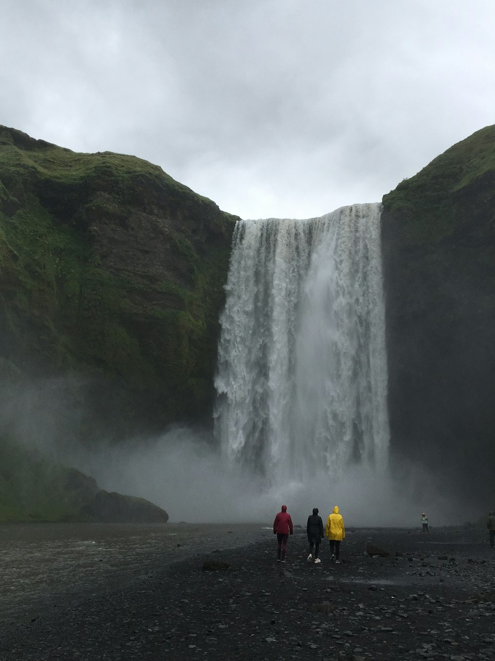 three person standing and looking waterfall