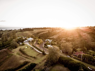 Sunset view over a rural land with rolling hills and a small farmhouse.