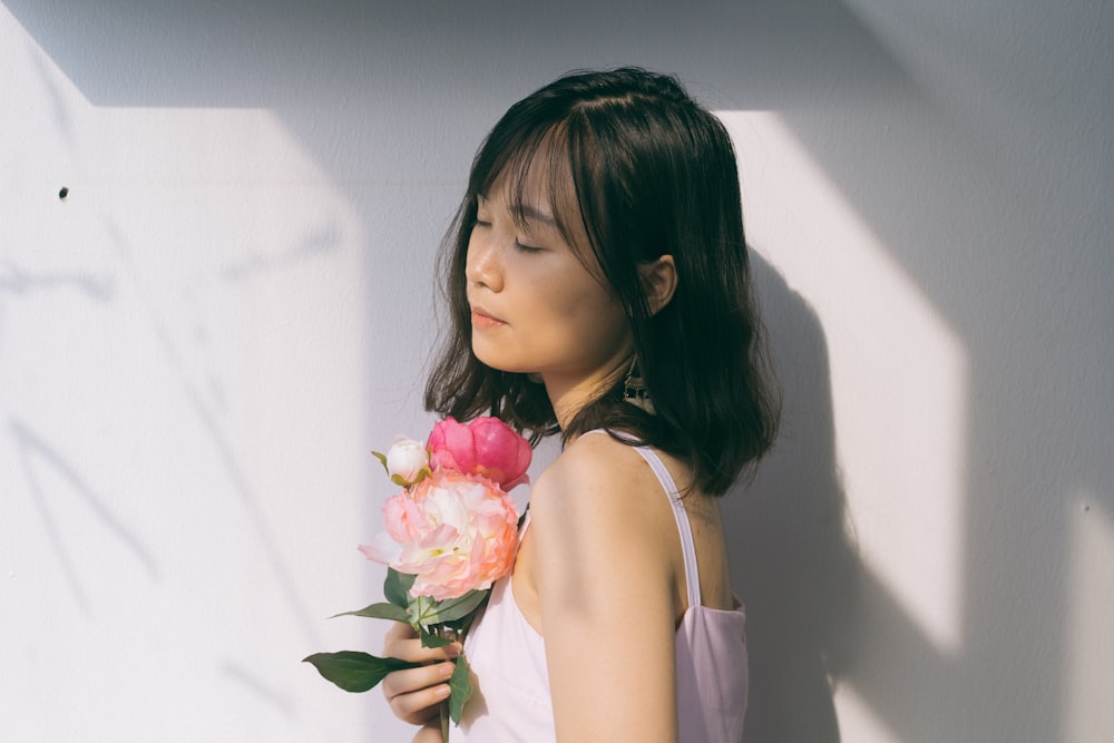 woman wearing pink top holding pink flowers