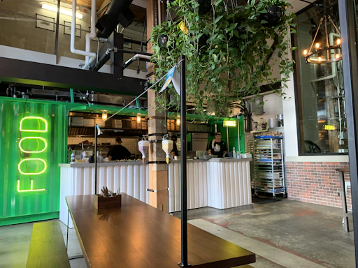 A modern urban restaurant interior with green neon accents and black walls.