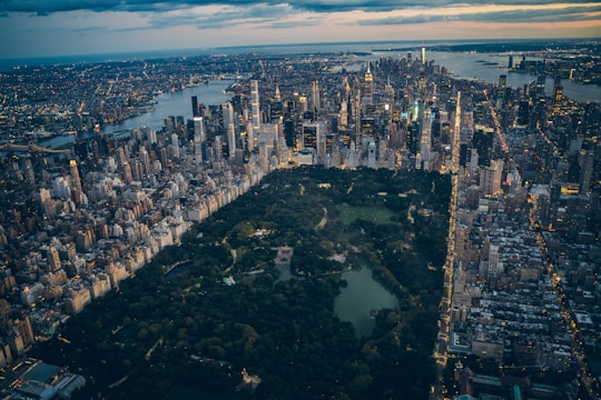 A vibrant aerial view of a city park seamlessly integrated with surrounding skyscrapers at sunset.