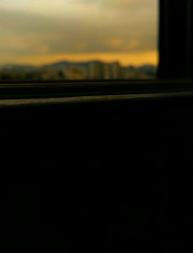 Soft-focus image of a city skyline under calm daylight filtering through glass windows.