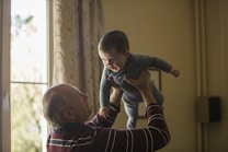 A grandfather lifting his grandchild, sharing family history through AI-powered ancestral stories.