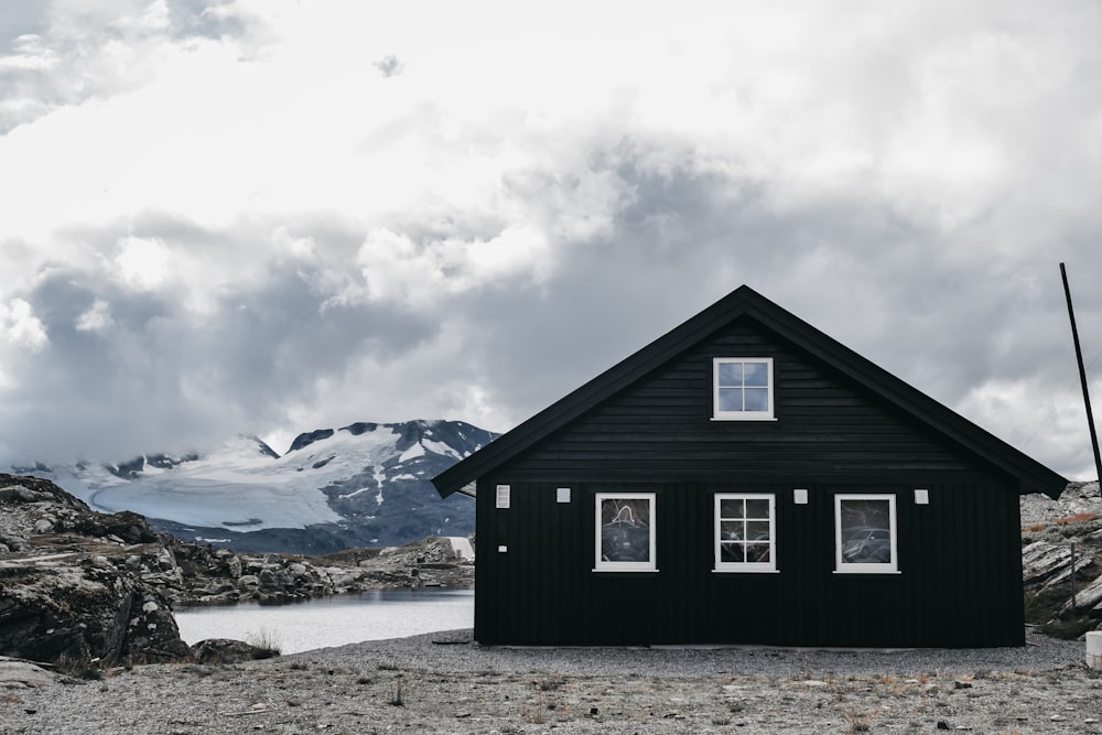 a black cabin with a mountain in the background