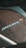 Close-up of a section of a vehicle featuring a textured, carbon-fiber-like surface with the McLaren logo prominently displayed, suggesting performance and luxury.