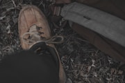 A close-up of a well-worn backpack and hiking boots resting beside a campfire.