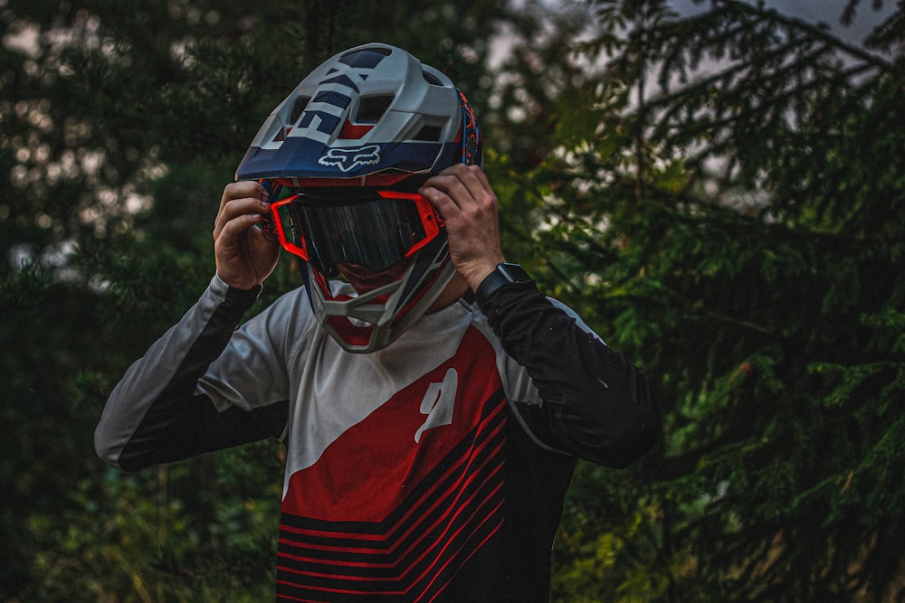 person holds helmet near trees