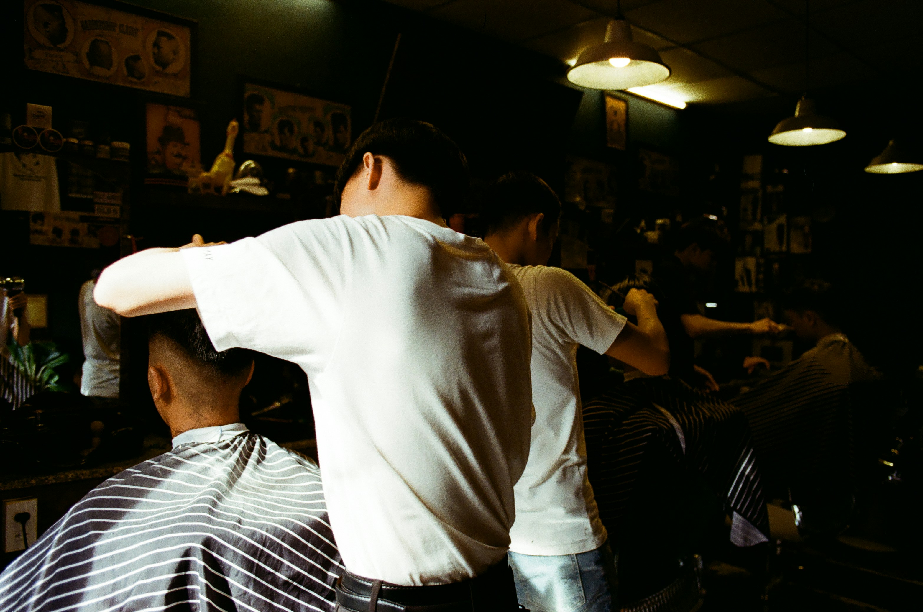 man cutting the hair of the person wears grey shirt