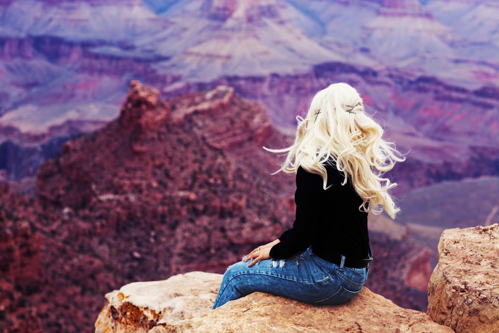 woman sitting on brown cliff during daytime