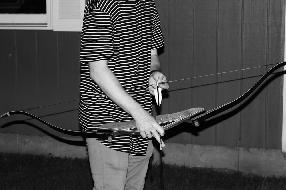 grayscale photo of person holding bow and arrow