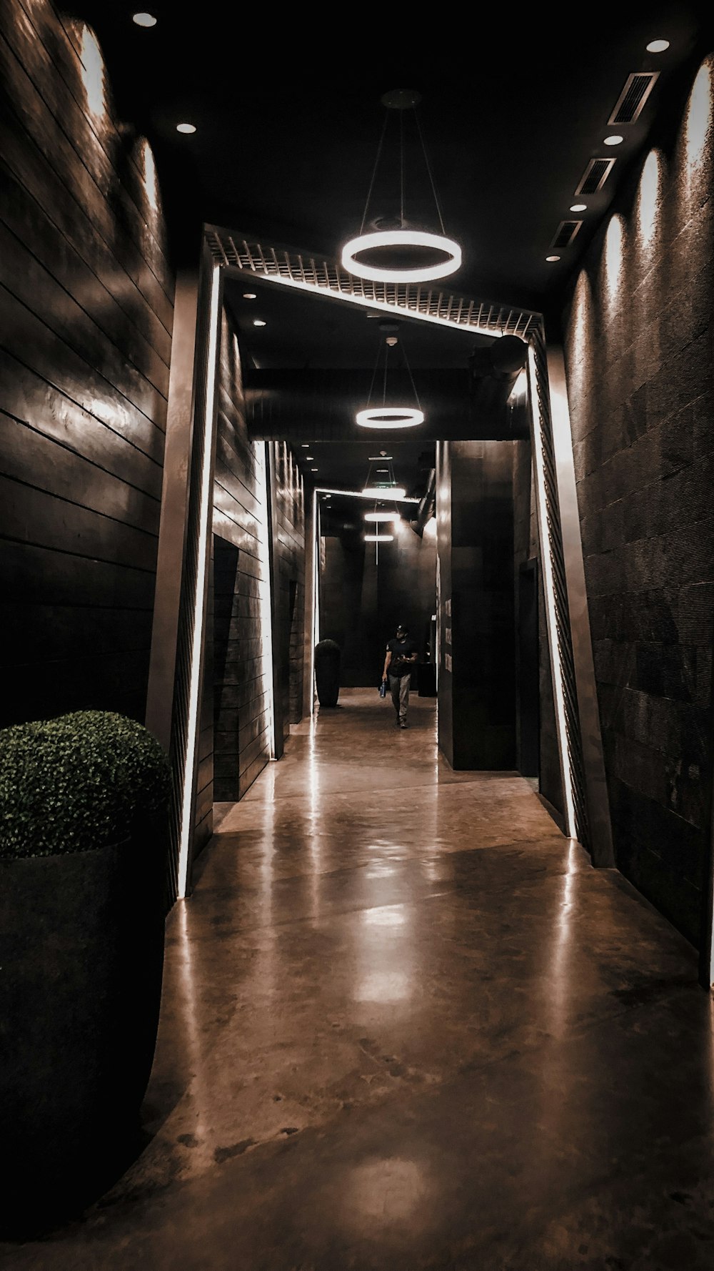 person walking on brown hallway with lights