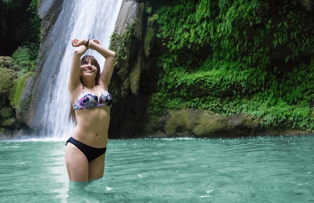 woman in black and white bikini near waterfalls during daytime