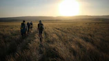 A group trekking through the rugged hills of Sindh at sunset.