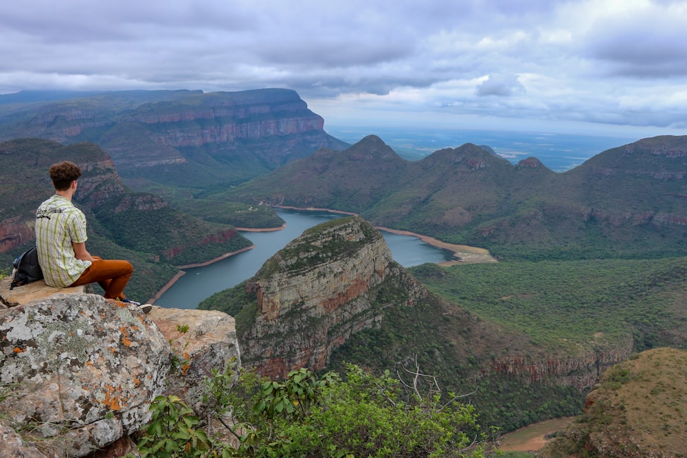 man sitting cliff rock