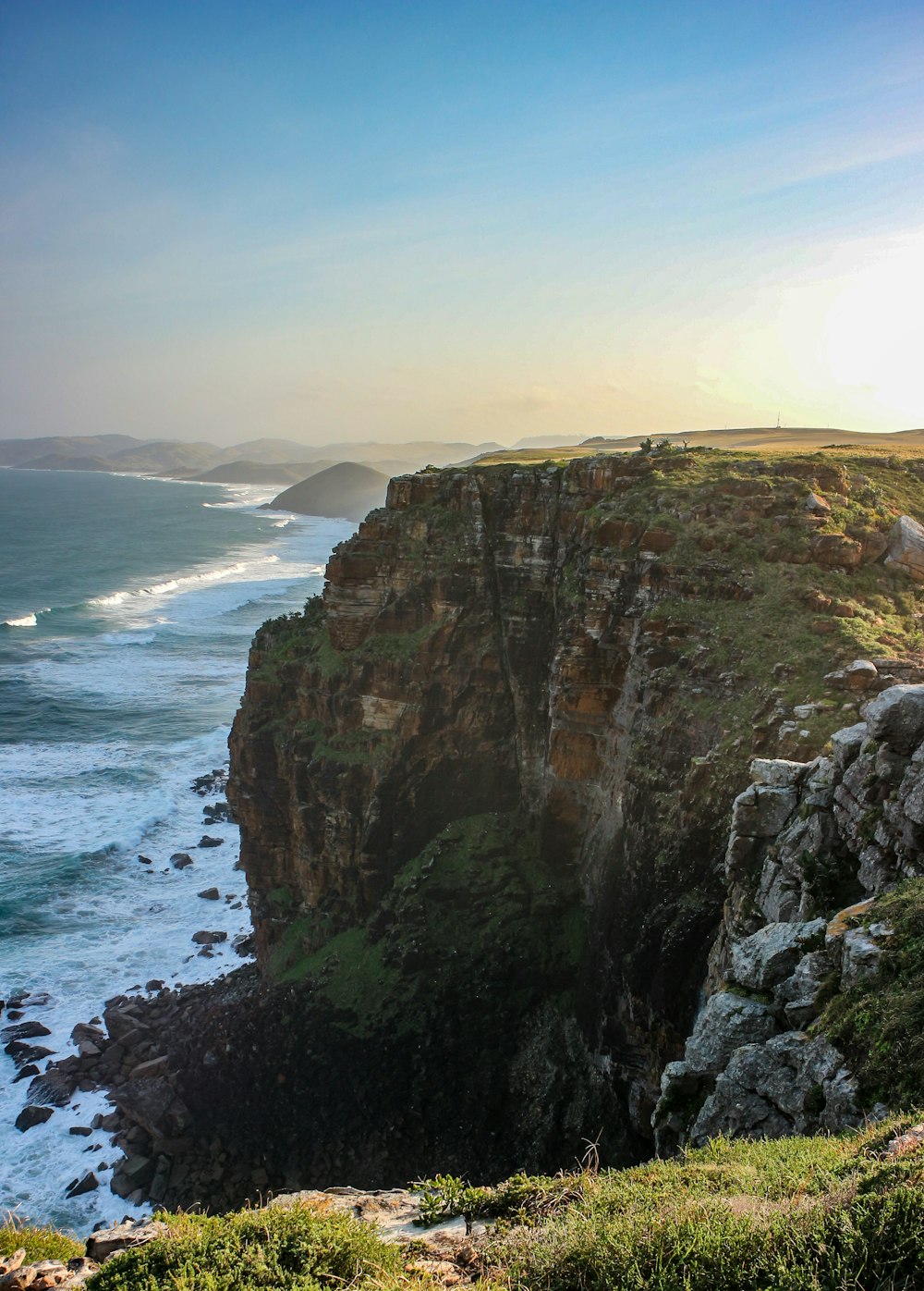 brown and green cliffs besides body of water