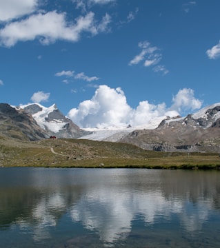 A calm lake surrounded by alpine mountains under a clear sky