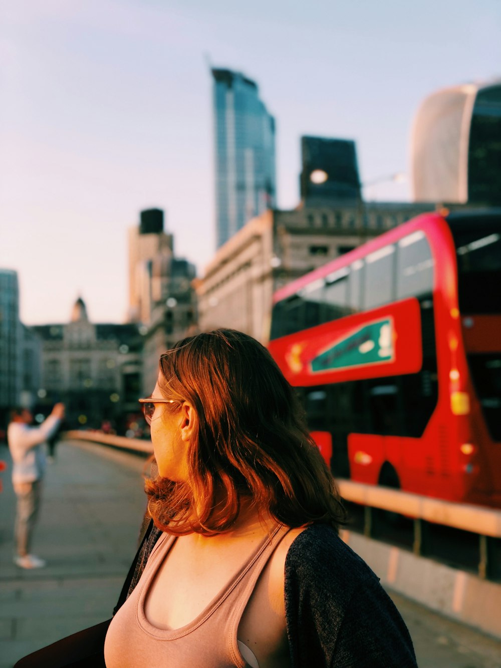 a woman standing next to a red double decker bus