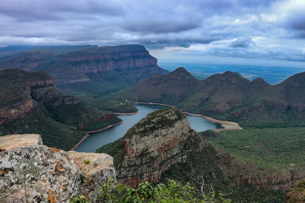 body of water and green mountain under blue sky